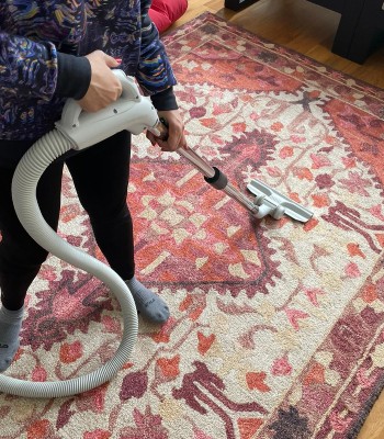 a girl cleaning floor metress with vaccum cleaner